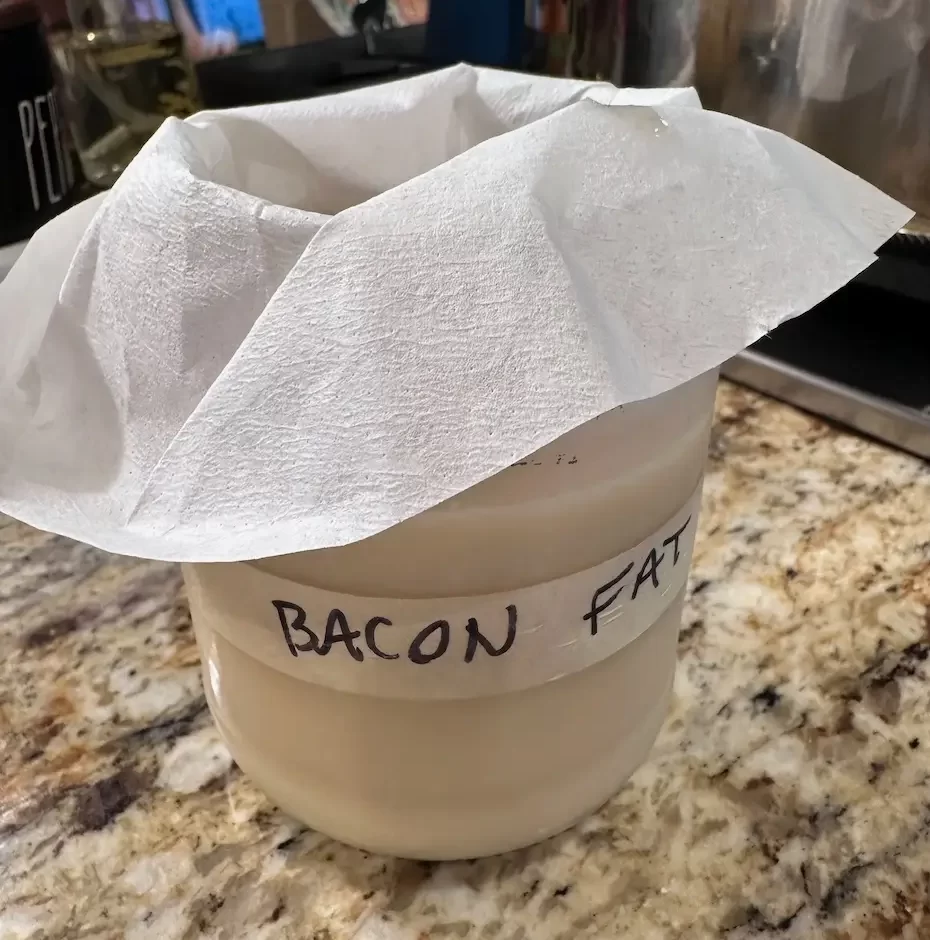 Using a coffee filter to strain the bacon bits out of the bacon fat