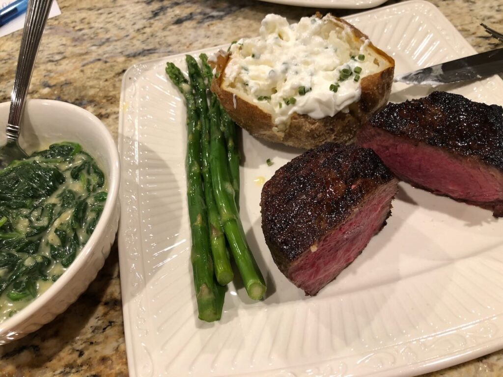 Cooked SRF manhattan filet with baked potato, asparagus and creamed spinach