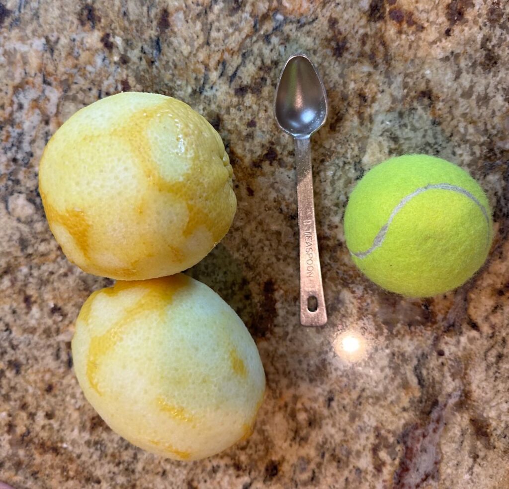 Two large lemons that were zested compared in size to a tennis ball. 