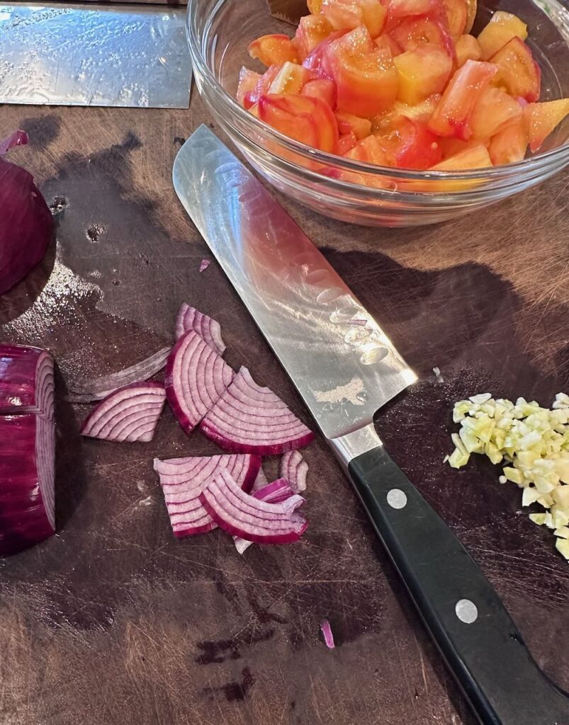 shown are quarter moon slices of onion getting ready for the heirloom tomato salad