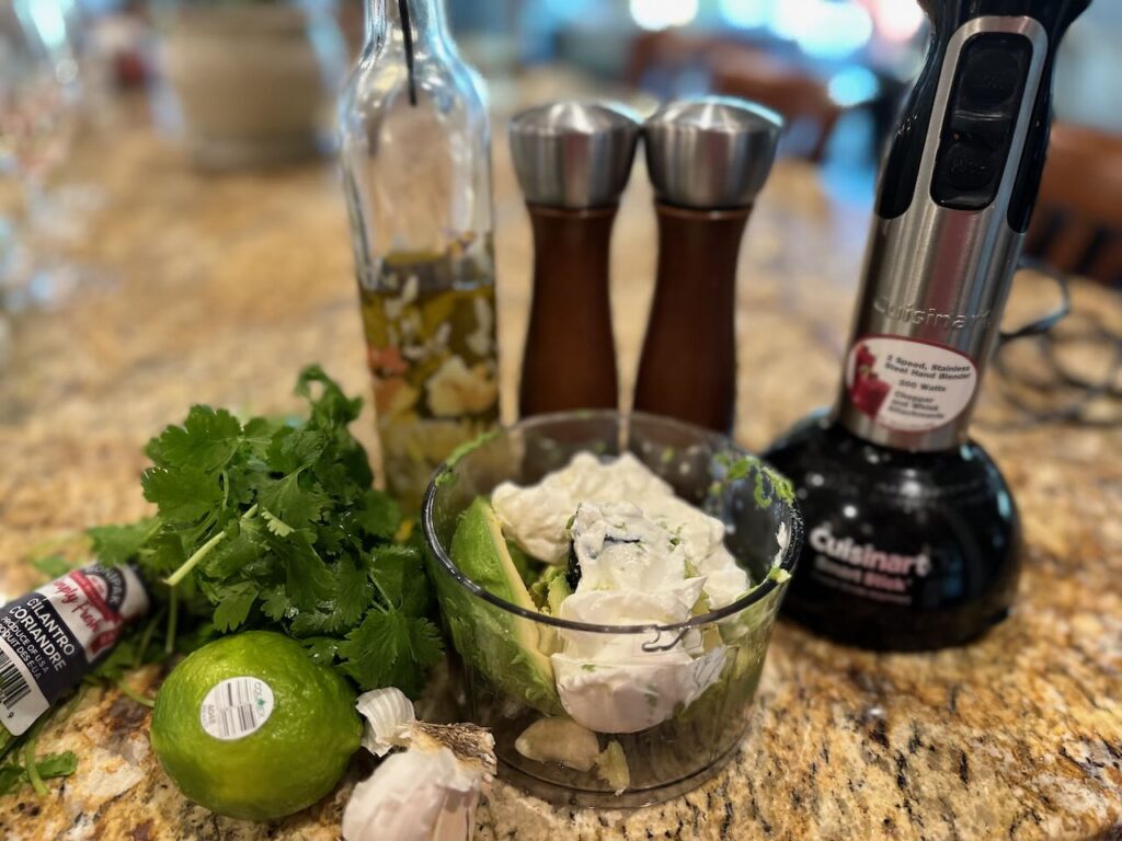 Two pictures of the avocado cilantro lime dressing being prepared in a mini food processor.  Before and after processing