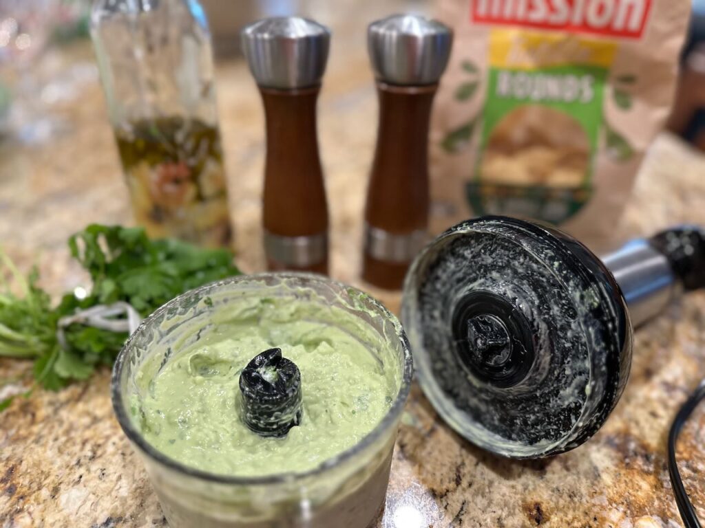 Two pictures of the avocado cilantro lime dressing being prepared in a mini food processor.  Before and after processing