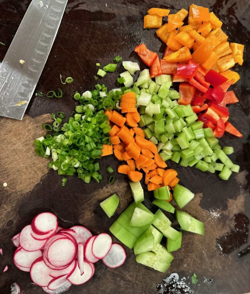 Cutting board shown with lots of veggies chopped 