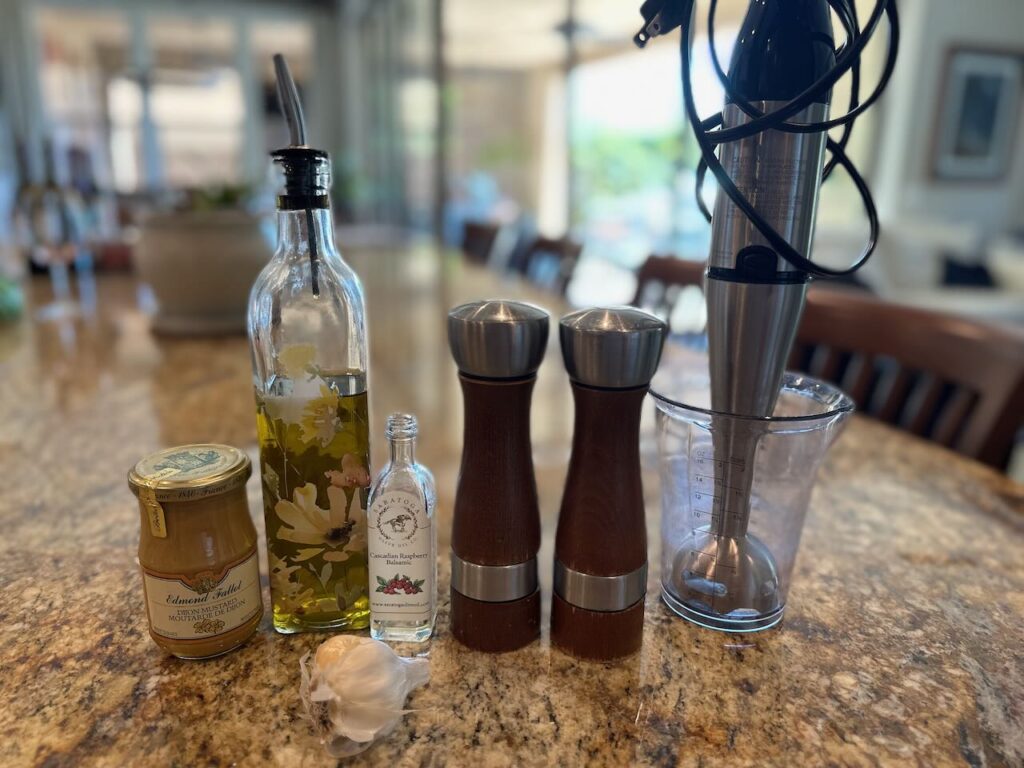 Ingredients for the homemade dressing - mustard, garlic, olive oil, and specialty vinegar.  Shown with an immersion blender 