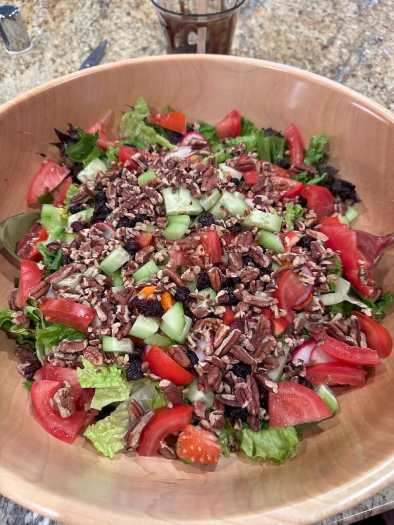 Giant salad with nuts, cranberries, tomatoes, cucumber, carrots, celery, radish, peppers, romaine and other greens. 