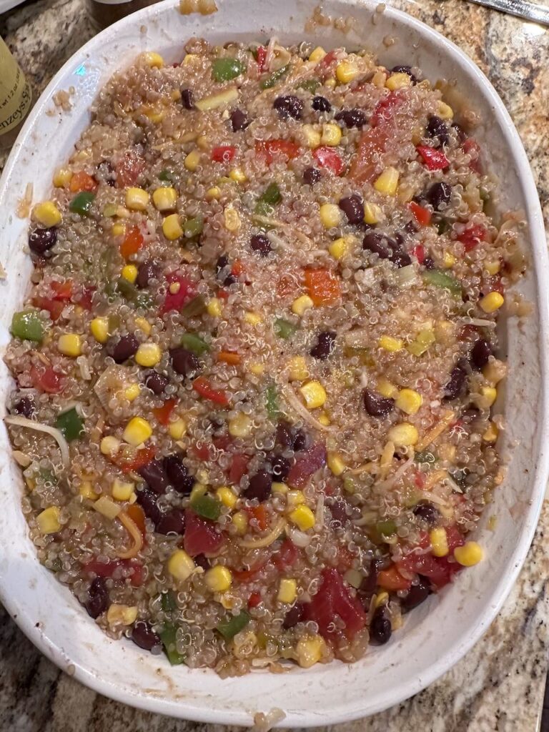 full casserole pan of quinoa, vegetables, black beans, enchilada sauce, spices and cheese. 