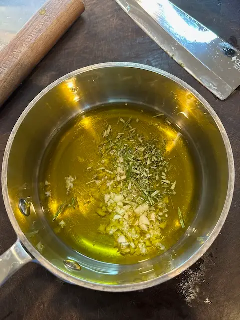 Starting the simmer ofherbs and garlic in olive oil on the stove.