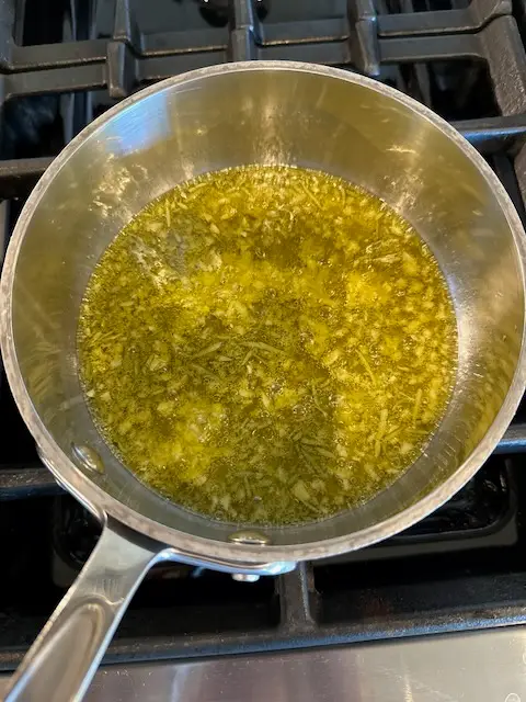 Simmering the herbs and garlic in olive oil on the stove.