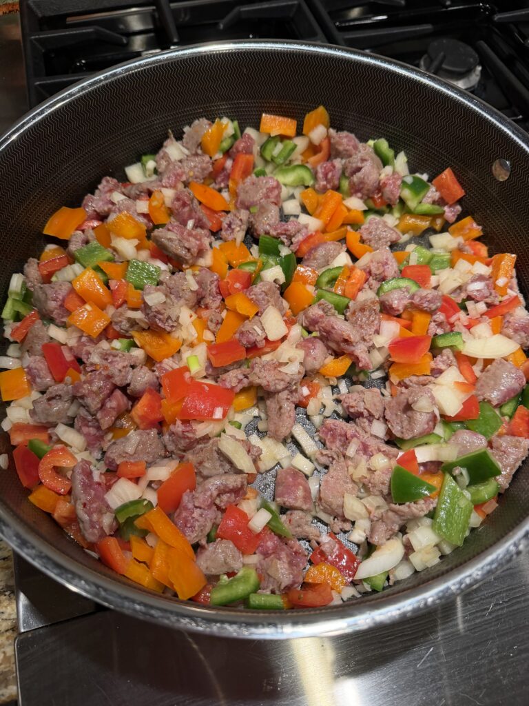 Saute pan of italian sausage and beautiful red, green and orange peppers. 